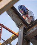 Welder wearing Wham 3030GB Solar Powered Welding Helmet With Pivot Headgear on metal beams at construction site
