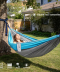 Single Portable Parachute Nylon Hammock For Outdoor Adventure hung between trees with a person relaxing in a garden