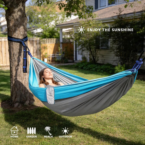 Single Portable Parachute Nylon Hammock For Outdoor Adventure hung between trees with a person relaxing in a garden