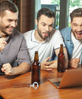 Metal bottle opener with wooden handle on wooden table; two beer bottles nearby, three men reacting in background.