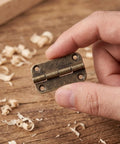 Antique Iron 12 Pack Old School Cabinet Hinges With Four Hole Mounting And Rounded Corners for Wood Boxes, shown close-up in hand
