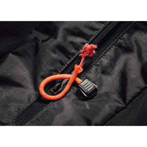 Close-up of TinderZIP Zipper Pull Fire Starter With Built In Tinder for emergency kits on black fabric zipper.