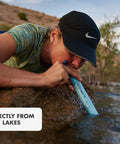 Person using Personal Water Purifier For Hiking Camping Travel And Emergency Prep Delivers Safe Drinking Water By Filtering Out Bacteria Parasites And Microplastics So You Can Stay Ready For Any Backcountry Adventure, drinking from stream