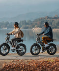 Two adults riding Powerful 1500W Peak Fat Tire Electric Bike For Adults With 20X4 Inch All Terrain Tires along a lakeside path.
