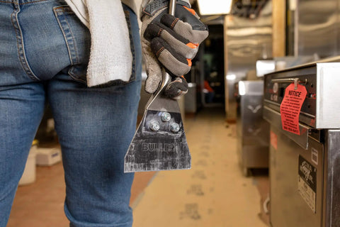Worker holding 5 In. By 11 In. SDS-Plus Bulldog Floor Scraper With Durable Steel Blade, Locking Bolt Attachment