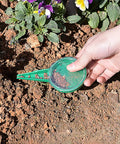 4 Pack Garden Hand Planter Seeder Tool Set with Adjustable Seed Dispenser in use for sowing seeds in soil near flowers.