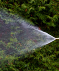 Adjustable Twist Garden Hose Nozzle With Heavy Duty Brass Sprayer 4 Inch Tip spraying mist in garden setting.