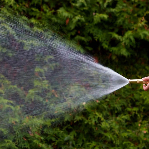 Adjustable Twist Garden Hose Nozzle With Heavy Duty Brass Sprayer 4 Inch Tip spraying mist in garden setting.