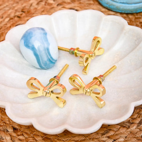 Set Of 8 Brass Bow Knobs For Cabinets And Drawers, Decorative Bow Hardware displayed on ceramic dish