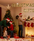 Family decorating Christmas tree and setting stockings by the fireplace with gifts under tree, Christmas gifts sign above.