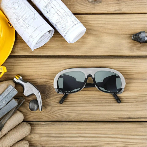 Killer Welding Safety Glasses With Dang Tough Scratch Proof Lens And Boss Level Spark Shield Featuring Slick Adjustable Fit And Comfortable Ear Hooks For Hard Working Crews In Ten Piece Bulk Pack on a wooden table with tools.