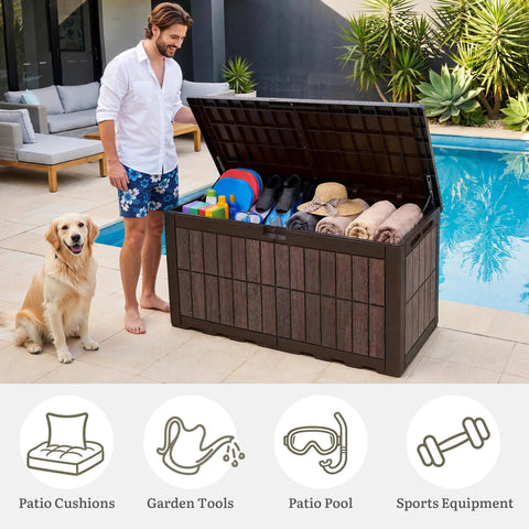 Man with dog using 134 Gallon Waterproof Resin Outdoor Deck Box with Lock, open, showing various outdoor essentials inside.