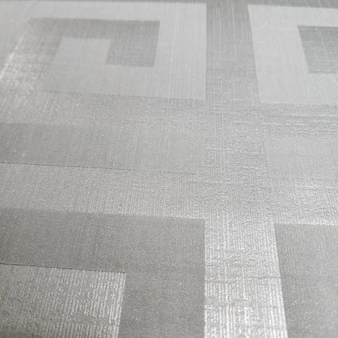 Close-up of Modern Geometric Greek Key Wallpaper With Metallic Matte Finish, showcasing textured gray silver pattern.