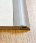 Close-up of 6.6 Ft Long Floor Transition Strip Edge Reducer For Rubber Wood Tile And Carpet Floors with gray beveled edge on wood floor.