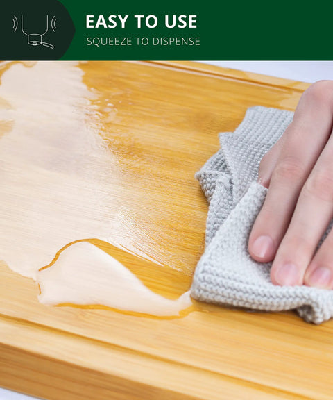 Hand using cloth to spread Food Grade Mineral Oil For Bamboo And Wooden Cutting Boards And Kitchen Utensils Nourishing Oil.