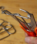Close-up of 12 Piece Pro Grade Miter Clamps with Carabiner Clip for woodworking projects showing metal clamps in use