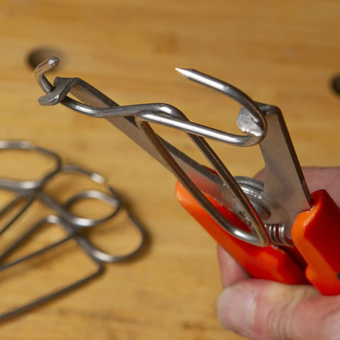 Close-up of 12 Piece Pro Grade Miter Clamps with Carabiner Clip for woodworking projects showing metal clamps in use