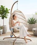 Woman sitting in a Hanging Egg Chair With Stand For Indoor And Outdoor Use Cozy Patio Rattan Swing Hammock Chair With Cushion 350 lb Capacity