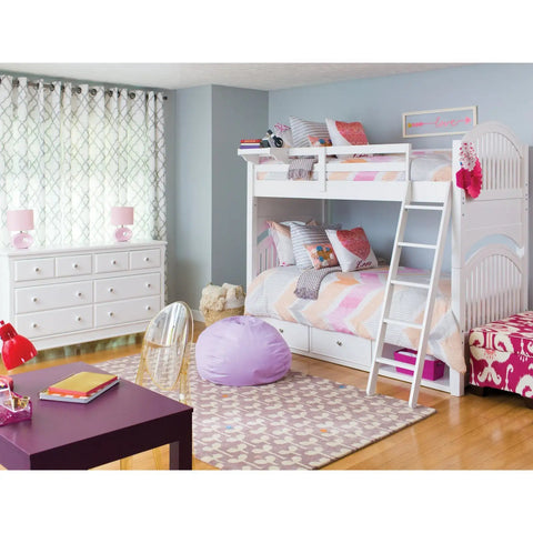 Modern bedroom with bunk beds, patterned rug, and purple accents, featuring cozy decor and colorful pillows in a bright setting.