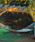 Outdoor hammock under a wooden pergola, surrounded by trees, featuring Outdoor Accents Mission Collection Decorative Post Base Covers on 6x6 posts.