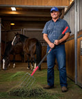 Man holding 5 Tine Pitch Fork Heavy Duty Manure Fork With Long Fiberglass Handle 58 Inch in horse stable