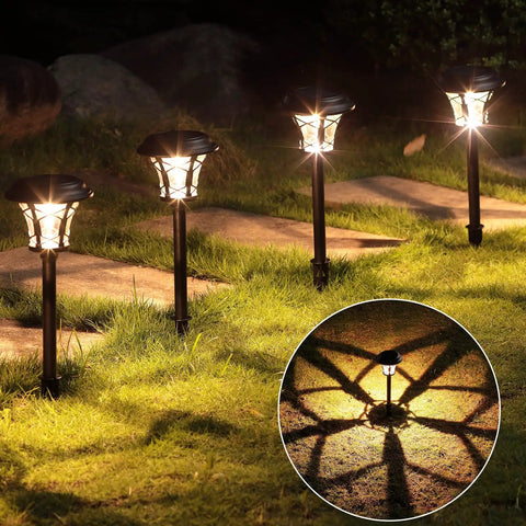 Four Eight Pack 25 Lumen Solar Powered Pathway Lights illuminating grass and stepping stones