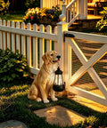 Golden Retriever Solar Dog Statue For Outdoor Decor With Lantern Lights Backyard Lawn Yard Art Weatherproof Garden Ornament For Patio Sun Powered Lights Lit Housewarming Gift beside fence at sunset.