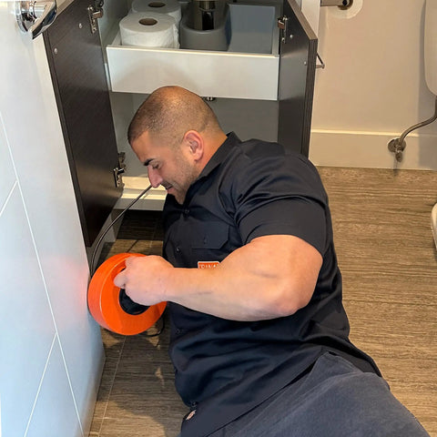 Man using Pro 50 Foot Heavy Duty Steel Drum Drain Auger Plumbing Snake With Work Gloves And Storage Bag for clog removal