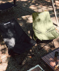 Oversized Padded Camping Chair with 27.6 Inch Wide Seat in green and black beside table in outdoor setting