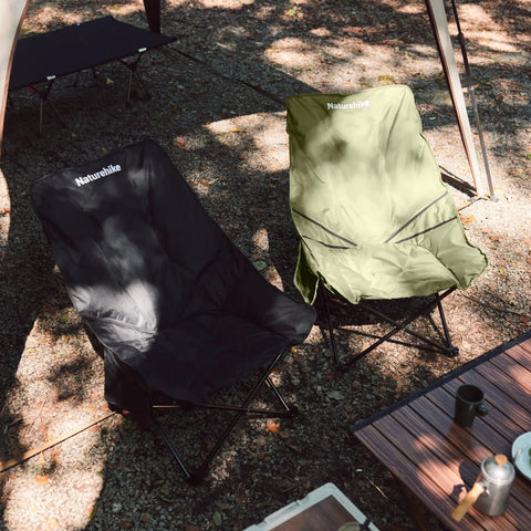 Oversized Padded Camping Chair with 27.6 Inch Wide Seat in green and black beside table in outdoor setting