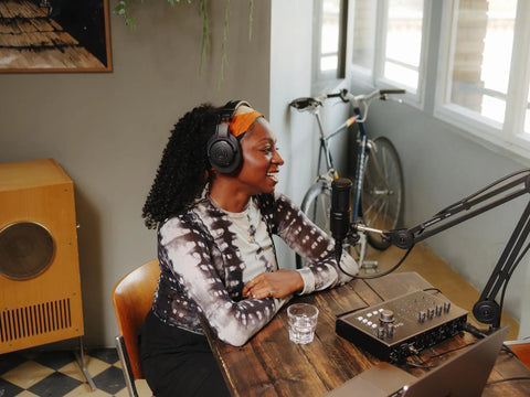 Person wearing M20x Professional Studio Headphones For Mixing And Monitoring at desk with microphone in home studio.