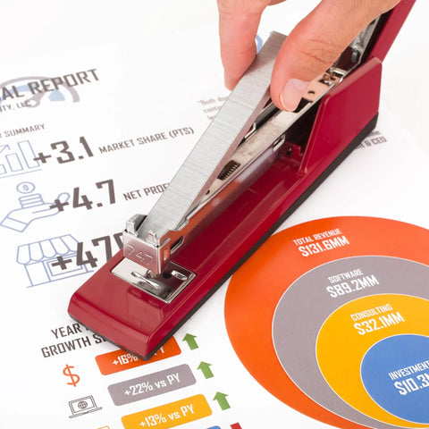 Hand placing Premium One Quarter Inch Staples, 210 Per Strip, Five Pack, 5000 Per Box in red stapler on office report.