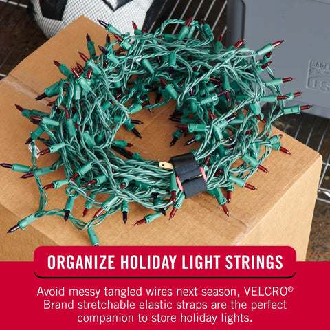 Elastic Cinch Straps With Buckle Two Pack securing holiday lights, displaying tensioned cords for cable management indoors.