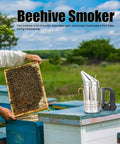 Heavy Duty Stainless Steel Electric Beekeeping Smoker With Heat Shield next to beehive frame in apiary setting.