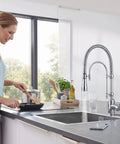 Ialtruistic 2-in-1 High Arc Pull Down Swivel Kitchen Faucet, Chrome in a modern kitchen with a woman cooking.