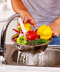 Person washing vegetables in kitchen sink demonstrating the need for H2O OK Plus Complete Water Analysis Kit with 23 tests.