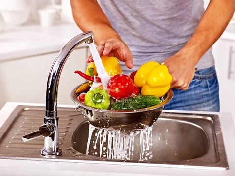 Person washing vegetables in kitchen sink demonstrating the need for H2O OK Plus Complete Water Analysis Kit with 23 tests.
