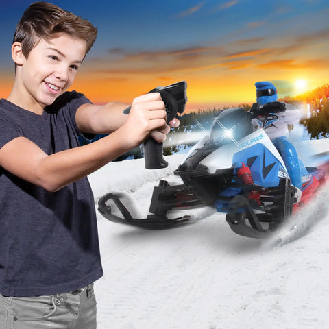 Child using controller with Switchback Assault RC Beast With Dual Ski System 2.4GHz RTR in snow, sunset backdrop