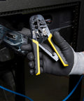 Person using Ratcheting Go-To Modular Crimping And Wire Stripping Tool For RJ22 RJ11 RJ12 RJ45 Connectors near network rack.
