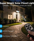 Ultra Bright Solar Flood Lights Outdoor With 7000 Lumens illuminating a house exterior with remote control in view