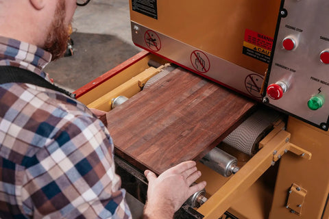 User operating Heavy Duty 16 Inch Open End Belt Sander 5 Hp 230V Single Phase Beast, feeding wood plank for sanding.