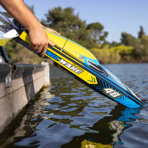 Person launching Sonicwake RC Boat 48 Inch Self Righting Brushless 8S Ready To Run into water near pier.