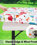 Floral 30x72 Inch Rectangle Vinyl Tablecloth with Elastic Edge snugly fitted on 6-foot table, ideal for outdoor use.
