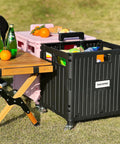Folding Utility Cart With Lid And Basket On Four 360 Degree Rotating Wheels in use outdoors next to a wooden table with drinks and oranges