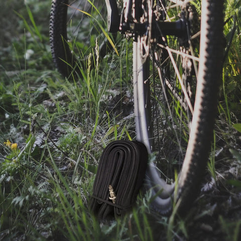 Road And Gravel Bike Inner Tubes 700C 18 To 25 Size With 48mm Presta Valve Pack Of 6 Durable Butyl Tubes next to bike tire on grass