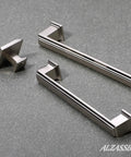 10 Pack Brushed Satin Nickel Cabinet Knobs 1.3 Inch Square Kitchen Cabinet Hardware Knobs For Cabinets And Drawers Dope Look Durable Solid Metal Knob Set For Furniture Dresser And Closet Projects. Image shows brushed satin nickel square knobs and matching handles on gray surface.