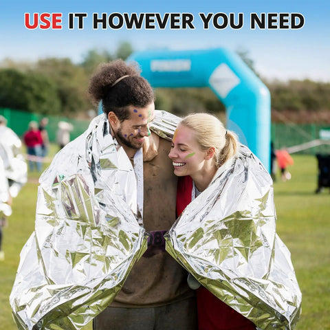 Couple wrapped in Extra Large 84 Inch By 63 Inch Thermal Mylar Emergency Blanket Kit at outdoor event