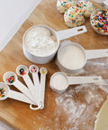 Eco-friendly wheat straw measuring cups and spoons on a wooden board, part of the Wheat Straw Measuring Cups And Spoons Set Ten Piece.