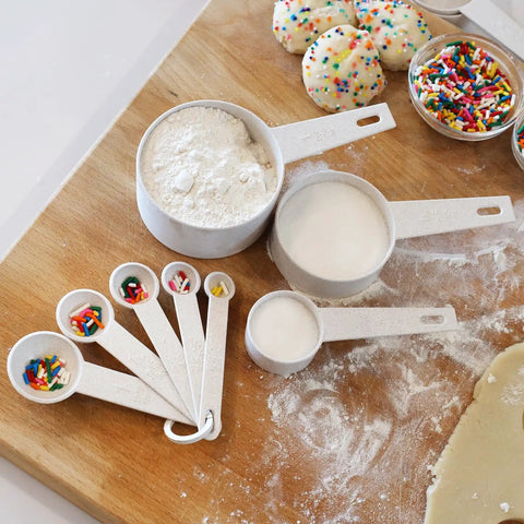 Eco-friendly wheat straw measuring cups and spoons on a wooden board, part of the Wheat Straw Measuring Cups And Spoons Set Ten Piece.