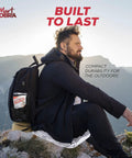 Man sitting outdoors with a backpack featuring Emergency Blanket 100 Pack Reflective Thermal Mylar Blankets For Survival Gear And First Aid Kits Retains Up To 90 Percent Body Heat Ultra Lightweight Perfect For Camping Outdoor Prep Grab And Go Ready Homeless Care Packages Bulk Disaster Readiness in the background.